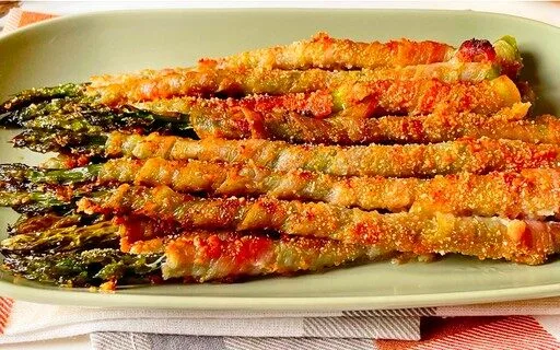 Metti le lance avvolte sulla griglia con il lato della cucitura rivolto verso il basso. Cuocere gli asparagi avvolti nella pancetta Cuocere gli asparagi avvolti nella pancetta per 10 minuti, girarli, quindi cuocerli per altri 10-15 minuti. Infine, imposta il forno sulla griglia e cuoci gli asparagi per 1 o 2 minuti, o fino a quando la pancetta diventa bella e croccante. Quanto tempo cuocere gli asparagi avvolti nella pancetta Gli asparagi avvolti nella pancetta richiedono un totale di 20-25 minuti nel forno , più un minuto o due in più sotto la griglia per rendere croccante la pancetta. Dovrai girare gli asparagi a metà cottura. Basta usare le tue comode pinze da cucina. Puoi preparare gli asparagi avvolti nella pancetta in anticipo? Sebbene questa sia una ricetta veloce, puoi risparmiare tempo preparando e avvolgendo gli asparagi con la pancetta una o due sere prima di pianificare di servirli. Tenerli avvolti in frigorifero, quindi semplicemente metterli in forno e servire. Variazioni di asparagi avvolti nella pancetta Puoi sostituire la pancetta con fette di prosciutto o jamon per un’opzione più sana e raffinata. Per un antipasto ancora più saporito, cospargere un po’ di parmigiano, cheddar o gorgonzola sugli asparagi. Puoi anche provare a condirli con dell’aceto balsamico, condire le lance con spezie come paprika, pepe di Caienna o condimento italiano, o aggiungere un po’ di sciroppo d’acero o zucchero di canna per caramellare la pancetta. Per un antipasto extralusso, usa gli asparagi bianchi al posto degli asparagi verdi. Suggerimenti per i migliori asparagi avvolti nella pancetta Gli asparagi avvolti nella pancetta sono naturalmente keto-friendly e senza glutine . Per rendere ancora più decadenti i tuoi asparagi avvolti nella pancetta, aggiungi un ripieno di crema di formaggio e aglio. Cuocere la pancetta fino a quando non è abbastanza croccante, quindi lasciarli scolare su un tovagliolo di carta. Unire la crema di formaggio ammorbidita e l’aglio, quindi versarne un po’ sulla pancetta. Avvolgere la pancetta intorno agli asparagi e infornare per 5 minuti a 400F. vedere il seguito alla pagina successiva